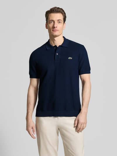 Männermodel trägt Regular Fit Poloshirt aus reiner katoen van Lacoste, look: effen, gestikt logo, polokraag, korte mouw, geribde rompzoom, geheel van katoen, ganzkörperansicht van voren.
