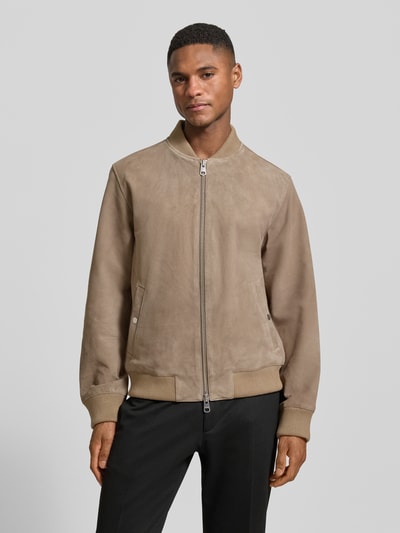 Männermodel trägt Regular Fit Wildlederjacken aus reinem Ziergenleder Modell 'ARCHIVE' von SELECTED HOMME in Beige, unifarben, Lederoptik, College-Kragen, Zweiwege-Reißverschluss, Rippenabschlüsse, seitliche Eingrifftaschen, Ganzkörperansicht von vorne.