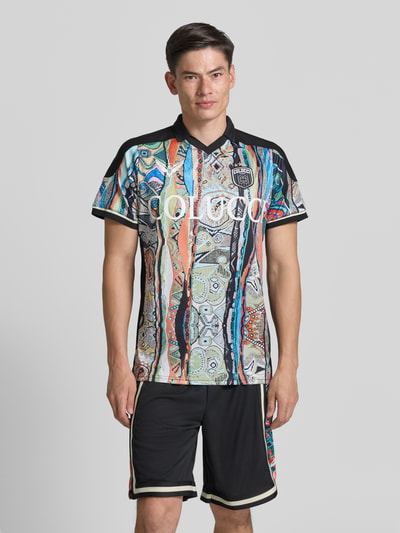 Männermodel trägt Slim Fit T-Shirt mit Label-Print von COLUCCI, bunte Muster, Polokragen, schwarze Details, Ganzkörperansicht von vorne.