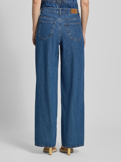 Frauenmodel trägt Wide Fit Jeans mit Ziernähten Modell 'Elsie' von YAS, 5-Pocket-Design, mittleres Blau, Struktur Denim, Ganzkörperansicht Rückansicht, Damen Jeans, Bundweite 37 cm, Innenbeinlänge 83 cm.