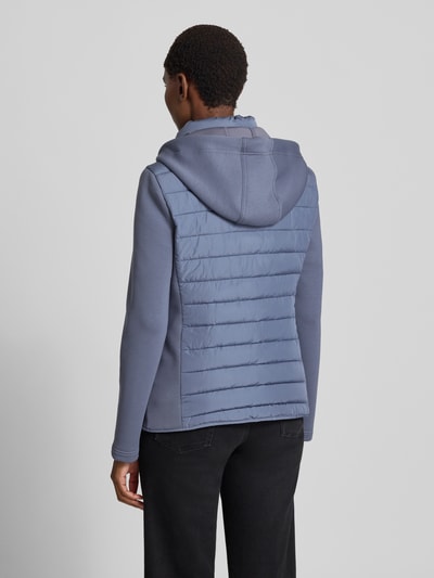 Vrouwenmodel draagt Steppjacke mit Kapuze und Reißverschlusstaschen van Christian Berg Woman Selection in regular fit, blauwe tinten, gevoerde textuur, ruglengte 59 cm, schouderbreedte 41 cm, borstwijdte 50 cm, mouwlengte 65 cm, volledige rugaanzicht.