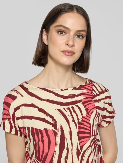 Frauenmodel trägt Relaxed Fit T-Shirt aus Viskose-Mix von s.Oliver RED LABEL mit Optik:Allover-Muster, Creme und Rot, Nahaufnahme Oberkörper.