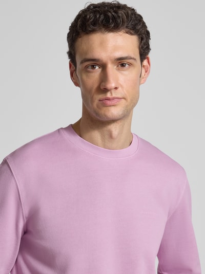 Männermodel trägt Regular Fit Sweatjacke aus reiner Baumwolle von Marc O'Polo in Uni-Rosa mit Label Print, Nahaufnahme Oberkörper.