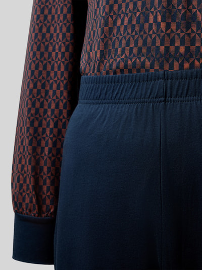 Männermodel trägt Regular Fit Pyjama-Set aus reiner Baumwolle von SCHIESSER, geometrisches Oberteil in Braun und Blau, elastischer Bund, Langarm, Knöchellänge, Nahaufnahme Oberkörper