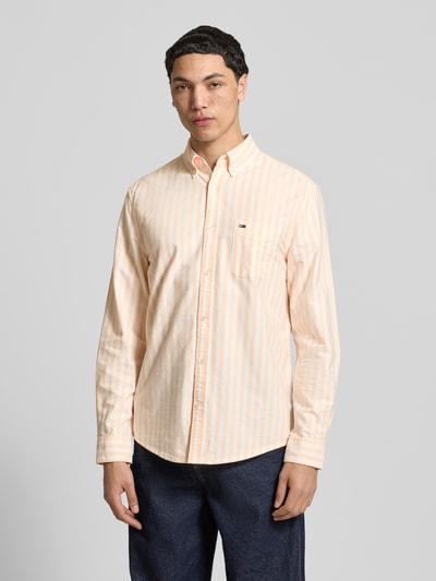 Männermodel trägt Regular Fit Freizeithemd aus reiner Baumwolle von Tommy Jeans, gestreiftes Allover-Muster, Ganzkörperansicht von vorne.