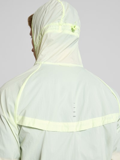 Männermodel trägt Trainingsjacke mit Logo-Print und Kapuze von NIKE TRAINING in hellgelb, Detailaufnahme Rückansicht, gerader Schnitt, Kapuze, Reißverschluss, Rückenlänge 71 cm, Ärmellänge 66 cm.