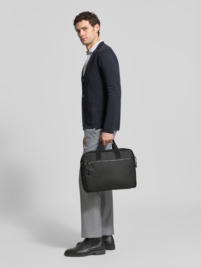Männermodel trägt Laptoptasche mit Label-Prints Modell 'Blanc Delight' von bugatti in Schwarz, Steck- und Reißverschlussfächer, Ganzkörperansicht von vorne.