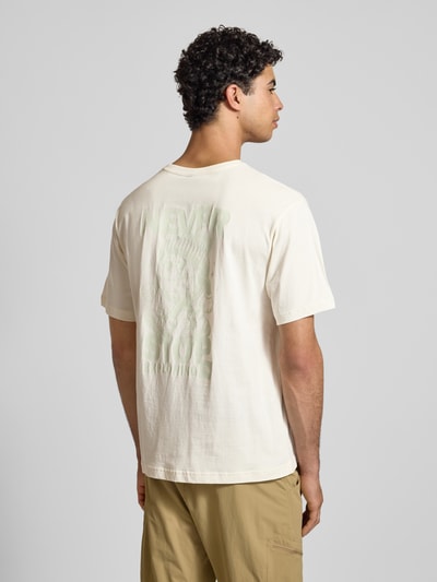 Männermodel trägt T-Shirt mit Label-Print von The North Face in Creme, Reine Baumwolle, Regular-Fit, gerippter Rundhalsausschnitt, Rückenlänge 69 cm, Ganzkörperansicht Rückansicht.