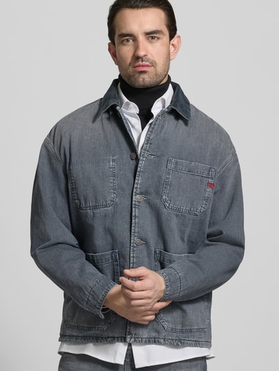 Männermodel trägt Regular Fit Hemdjacke in Denim-Optik von Diesel aus reiner Baumwolle, graublaue Farbe, AufgesetzteTaschen, Knopfleiste, Ganzkörperansicht von vorne.