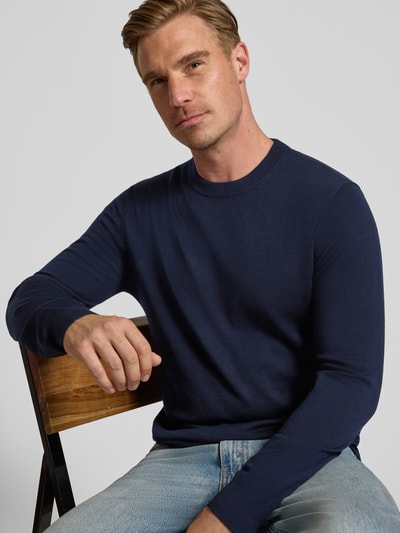 Männermodel trägt dunkelblauen Regular Fit Pullover aus reiner Wolle von Jake*s Studio Men, kombiniert mit hellblauer Jeans, Nahaufnahme Oberkörper.