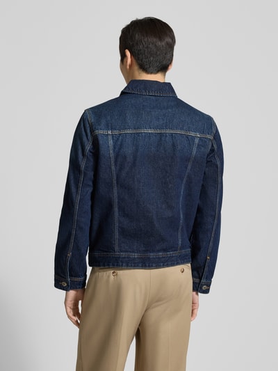 Męski model nosi Jeansjacke mit Brusttaschen von MCNEAL, granatowa bawełna, krój regular fit, widok całej sylwetki z tyłu. Szerokość w rozmiarze M: 48 cm, długość tyłu: 62 cm, szerokość klatki: 27 cm, długość rękawa: 64 cm.