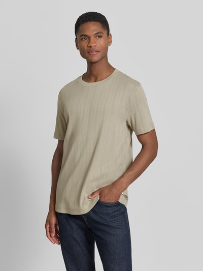 Männermodel trägt T-Shirt in Jaquard-Strick mit Rundhalsausschnitt von Lindbergh aus Reine Baumwolle, Regular-Fit, Label-Detail, Rückenlänge 72 cm, sandfarben, dezentes Jaquard-Muster, Ganzkörperansicht von vorne.