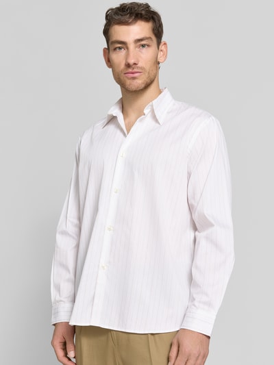 Männermodel trägt Relaxed Fit Freizeithemd aus reiner Baumwolle Modell 'GEORGE' von SELECTED HOMME, weiß mit feinen Streifen, Popeline, Knopfleiste, Haifischkragen, Ganzkörperansicht von vorne.