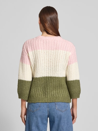 Frauenmodel trägt Strickpullover mit Rundhalsausschnitt von More & More im Relaxed-Fit Grobstrick Material-Mix mit Baumwoll-Anteil, Rückenlänge 55 cm, Ärmellänge 48 cm, breite Streifen in Rosa, Creme und Oliv, Ganzkörperansicht Rückansicht.