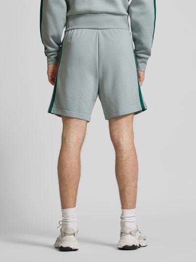 Männermodel trägt Regular Fit Shorts mit Viskose-Anteil von adidas Sportswear, hellgrau, Baumwoll-Mix, elastischer Bund, Logo-Stitching, Ganzkörperansicht Rückansicht.
