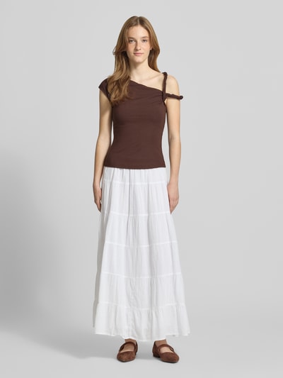 Modelka kobieca ma na sobie Top im One-Shoulder-Look model 'Fenna' od LeGer by Lena Gercke, kolor brązowy, krój slim fit, mieszanka wiskozy i elastanu, długość tyłu w rozmiarze 36: 48 cm, długa biała spódnica, brązowe baleriny, widok całej sylwetki z przodu.