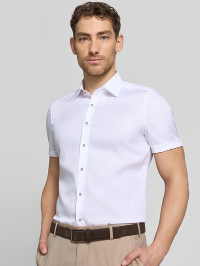 Męski model nosi Slim Fit Business-Hemd mit Kentkragen od OLYMP Level Five, biała bawełna, krój slim fit, guzik, mankiet, długość tyłu w rozmiarze 40: 70 cm, szerokość ramion w rozmiarze 40: 40 cm, długość rękawa w rozmiarze 40: 24 cm, zdjęcie całej sylwetki z przodu.