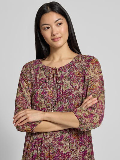 Frauenmodel trägt Knielanges Kleid mit Schlüssellochausschnitt von ZABAIONE in Falten-Optik, gemustert in Rosa, Lila und Beige, Relaxed Fit, 1/2-Arm, Nahaufnahme Oberkörper.