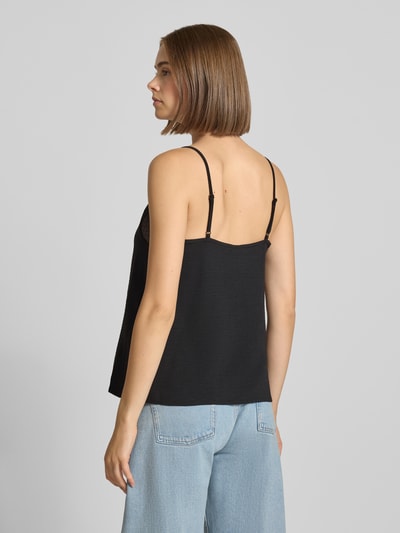 Frauenmodel trägt schwarzes Loose Fit Blusentop mit Spitzenbesatz Model 'TIFFANY' von PIECES, kombiniert mit hellblauer Jeans, Ganzkörperansicht Rückansicht. Damen Blusentop von PIECES.