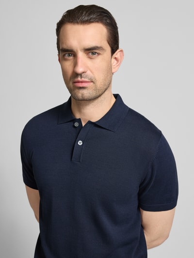 Męski model nosi Koszulka polo Regular Fit Poloshirt in Strick-Optik Model 'Josh' od Christian Berg Men z bawełny, imitacja dzianiny, krótki rękaw, kołnierzyk polo, elastyczne wykończenia, kolor granatowy, zbliżenie na górną część ciała.