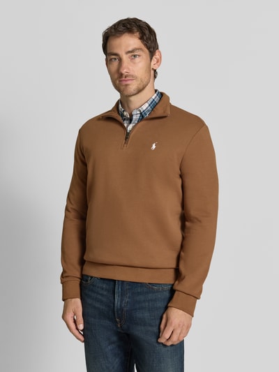 Männermodel trägt Relaxed Fit Troyer aus Baumwoll-Mix von Polo Ralph Lauren in Braun, kombiniert mit Jeans, Ganzkörperansicht von vorne.