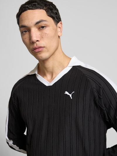 Männermodel trägt Relaxed Fit Polo-Longsleeve mit Label-Stitching von PUMA PERFORMANCE, V-Ausschnitt, reine Baumwolle, Nahaufnahme Oberkörper.