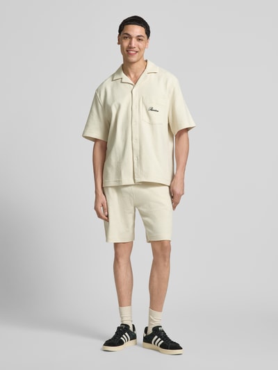 Männermodel trägt Regular Fit Freizeithemd mit Label-Stitching von REVIEW aus Baumwoll-Mix, Farbe Creme, Reverskragen, Brusttasche, Ganzkörperansicht von vorne. Rückenlänge bei Größe M: 71 cm, Schulterbreite: 54 cm, Ärmellänge: 29 cm.