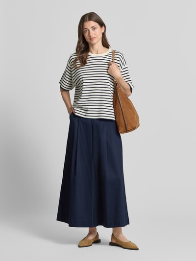 Vrouwenmodel draagt Wide Fit Stoffhose mit Bundfalten van Christian Berg Woman in donkerblauw katoen met verkorte pasvorm, voorkant volledig lichaam.