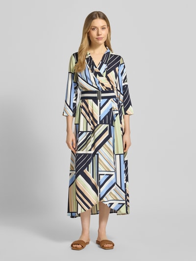 Modelka nosi Regular Fit Maxikleid in Wickel-Optik od Betty Barclay, geometryczne wzory, pasek, kołnierz szalowy, długość tyłu 128 cm, szerokość w rozmiarze 36: 31 cm, długość rękawa 46 cm, widok całej sylwetki z przodu.