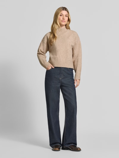 Vrouwenmodel draagt Turtleneck-Pullover met Woll-Anteil und Rundhalsausschnitt van Neo Noir, Materiaalmix met wol, recht model, ribboorden, ruglengte maat 36: 53 cm, mouwlengte maat 36: 53 cm, gebreide textuur in beige, donkerblauwe broek, Ganzkörperansicht van voren.