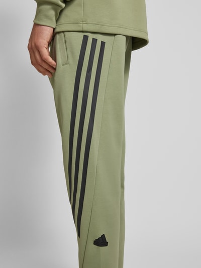 ADIDAS SPORTSWEAR Spodnie dresowe o kroju tapered fit z charakterystycznymi dla marki paskami Oliwkowy 3