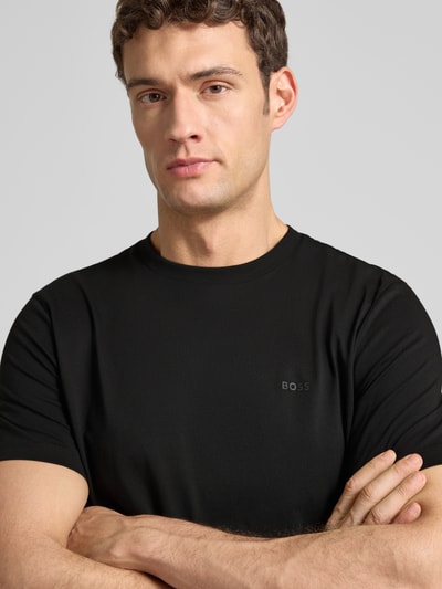 Männermodel trägt T-Shirt aus Baumwolle Modell 'Thompson' von BOSS in Schwarz, dezenter Logo-Print, Nahaufnahme Oberkörper.