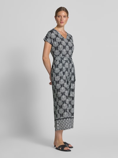 Frauenmodel trägt Jumpsuit mit floralem Allover-Print von MORE & MORE in Schwarz-Weiß, taillierte Passform, Ganzkörperansicht von vorne.