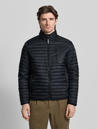 Männermodel trägt Steppjacke mit Stehkragen von camel active in Schwarz mit Reißverschlusstaschen, Ganzkörperansicht von vorne. Regular Fit, glatte Textur, Größenangaben: Rückenlänge 27 cm, Schulterbreite 19 cm, Brustweite 22 cm, Ärmellänge 27 cm.