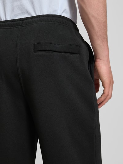 Männermodel trägt Sweatpants mit Logo-Stitching und Eingrifftaschen von Nike aus Baumwoll-Mix, locker geschnitten, Detailaufnahme Rückansicht.