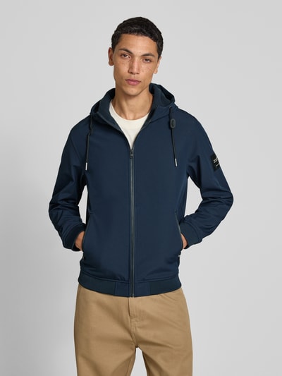 Männermodel trägt Regular Fit Jacke mit Logo-Detail von JACK & JONES in Dunkelblau, Kapuze, Reißverschlusstaschen, Nahaufnahme Oberkörper.
