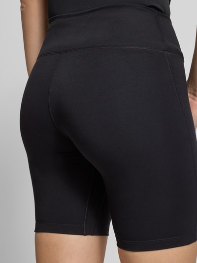 Frauenmodel trägt Shorts mit Logo-Print Modell 'One' von NIKE TRAINING aus schwarzem Material-Mix mit Stretch-Anteil, Detailaufnahme Rückansicht.