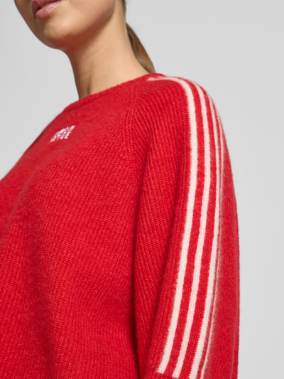 Frauenmodel trägt Cropped Strickpullover mit gerippten Abschlüssen Modell 'VITOW' von American Vintage, leuchtend rot mit weißen Streifen, Woll-Alpaka-Mix, lockerer Schnitt, Nahaufnahme Oberkörper.