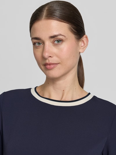Kobieta nosi Regular Fit Kurzarmbluse mit Rundhalsausschnitt von Christian Berg Woman Selection, granatowy kolor, elastyczne zakończenia rękawów, krótki rękaw, gładka tekstura, zbliżenie na górną część ciała