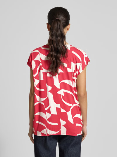 Vrouwenmodel draagt Regular fit blouse uit viscosemix model 'Minou' van ZABAIONE met all-over bloemenprint, ruglengte maat S 62 cm, short sleeves, ronde hals, elastische band, overwegend rood met wit patroon, ganzkörperansicht rückansicht.