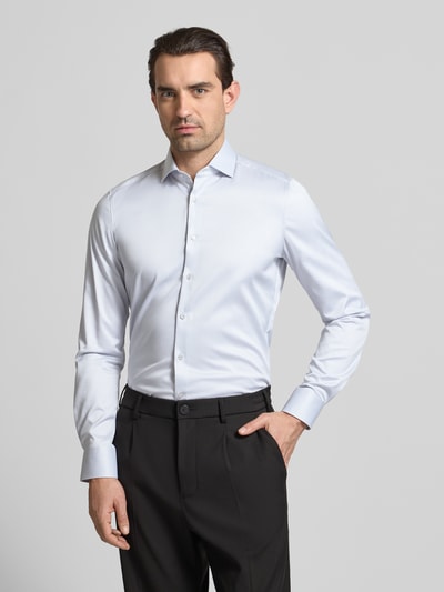 Männermodel trägt Slim Fit Business-Hemd in unifarbenem Design mit Kentkragen von OLYMP Level Five aus reiner Baumwolle, Ganzkörperansicht von vorne.