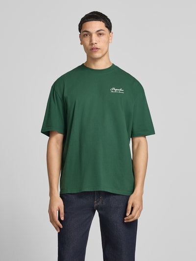 Männermodel trägt Oversized Fit T-Shirt mit Label-Detail Modell 'Morcote' von Pegador, grün, Reine Baumwolle, Rundhalsausschnitt, Halbarm, Herren T-Shirt, Rückenlänge bei Größe M: 70 cm, Ganzkörperansicht von vorne.