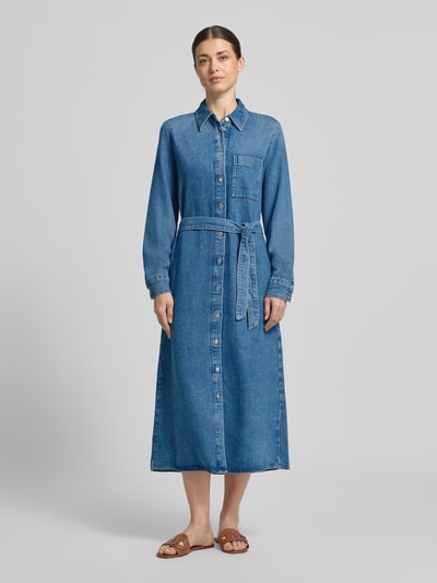 Modelka nosi Midi-Jeanskleid aus Lyocell-Baumwoll-Mix von Marc O'Polo, tkanina stylizowana na denim, krój regular fit, długość midi, wysoki dekolt, szlufki na pasek, szwy w kontrastowym kolorze, pas na plecach, pasek w talii, listwa guzikowa, długi rękaw, zakończenie rękawów mankietem, dół prosty, wpuszczane kieszenie, mieszanka lyocellu i bawełny, zdjęcie całej sylwetki z przodu.