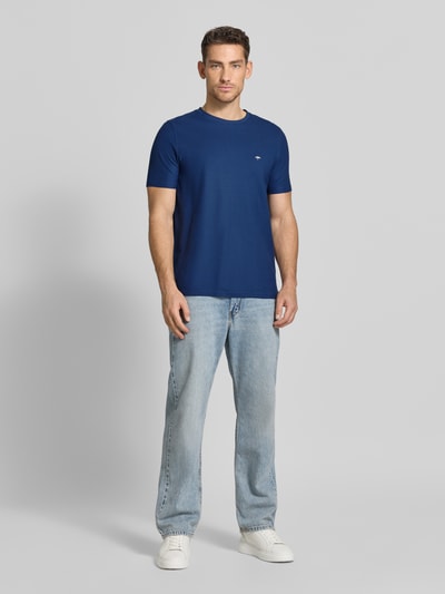 Mężczyzna nosi Regular Fit T-Shirt mit Logo-Stitching od Fynch-Hatton, kolor niebieski, bawełna, krój regular fit, widok całej sylwetki z przodu.