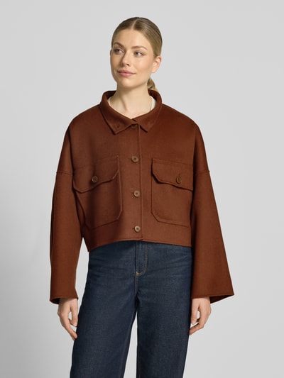 Frauenmodel trägt Boxy Fit Jacke mit Pattentaschen Modell 'ARKLOW' von DRYKORN aus braunem Baumwoll-Mix, Knopfleiste, Ganzkörperansicht von vorne. Rückenlänge 51 cm, Schulterbreite 78 cm, Brustweite 73 cm, Ärmellänge 43 cm.