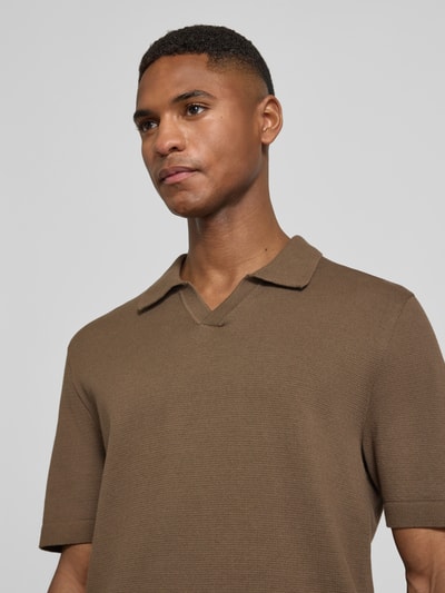 Mannenmodel draagt gebreid shirt met v-hals en platte kraag van katoenmix, model 'MILANO' van Jack & Jones Premium, recht model, labeldetail, ruglengte bij maat M 69 cm, close-up bovenlichaam.