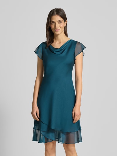 Modelka kobieca ma na sobie knielanges Cocktailkleid mit Wasserfall-Ausschnitt od Christian Berg Cocktail, turkusowy szyfon, krój A-linia, widok całej sylwetki z przodu.