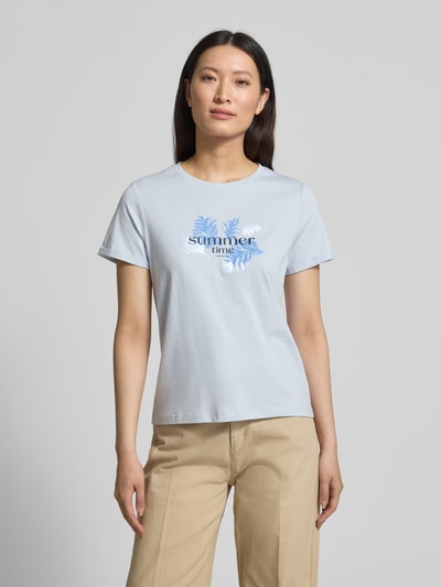 Frauenmodel trägt Regular Fit T-Shirt aus reiner Baumwolle von Tom Tailor in Optik: Unifarben mit Motiv-Print, Label-Print, Rundhals, Ärmelform: Kurzarm, fixierter Umschlag, Materialverarbeitung: Jersey, Farbe Hellblau, Textur glatt, Ganzkörperansicht von vorne.