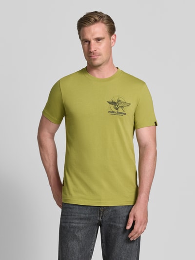 Męski model nosi t-shirt z nadrukiem z logo i okrągłym dekoltem T-Shirt mit Label-Print und Rundhalsausschnitt von PME Legend, bawełna, krój slim fit, długość tyłu w rozmiarze M: 71 cm, zielony kolor, prosty fason, gładka tekstura, całkowity widok z przodu.