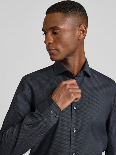 Männermodel trägt Slim Fit Businesshemd aus Baumwolle mit Kentkragen von OLYMP Level Five, dunkler Farbton, dezentes Muster, Nahaufnahme Oberkörper.